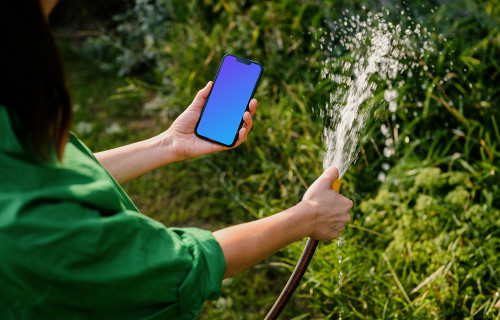 Mulher segurando um iPhone enquanto rega plantas mockup