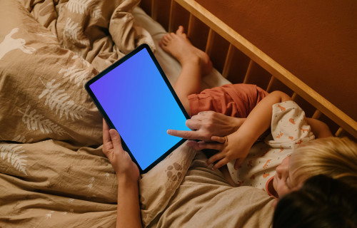 Mulher com uma criança digitando em um iPad mockup na cama