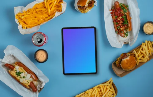 Tablet mockup surrounded by hot-dogs and fries