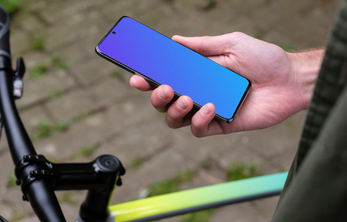 Segurando o Samsung S20 mockup em uma mão ao lado de uma bicicleta
