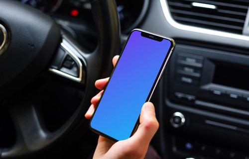 Drivers hand holding iPhone 11 mockup from behind the wheel