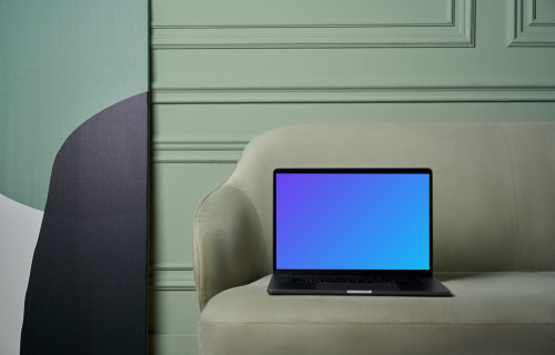MacBook mockup em um sofá com pintura ao lado
