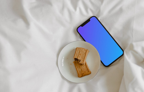 iPhone 12 Pro mockup na cama com um prato de biscoitos