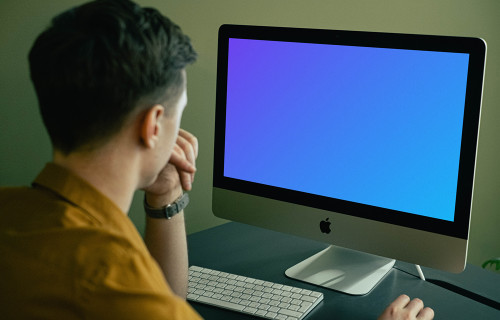 Mockup de usuário olhando para seu iMac enquanto trabalha